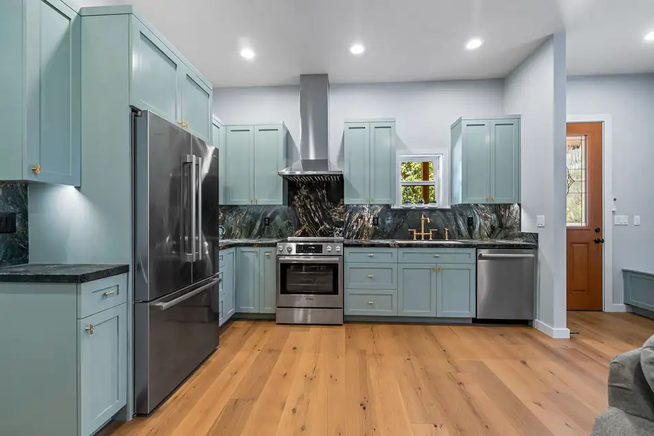 ADU kitchen with sage cabinets and marble backsplash